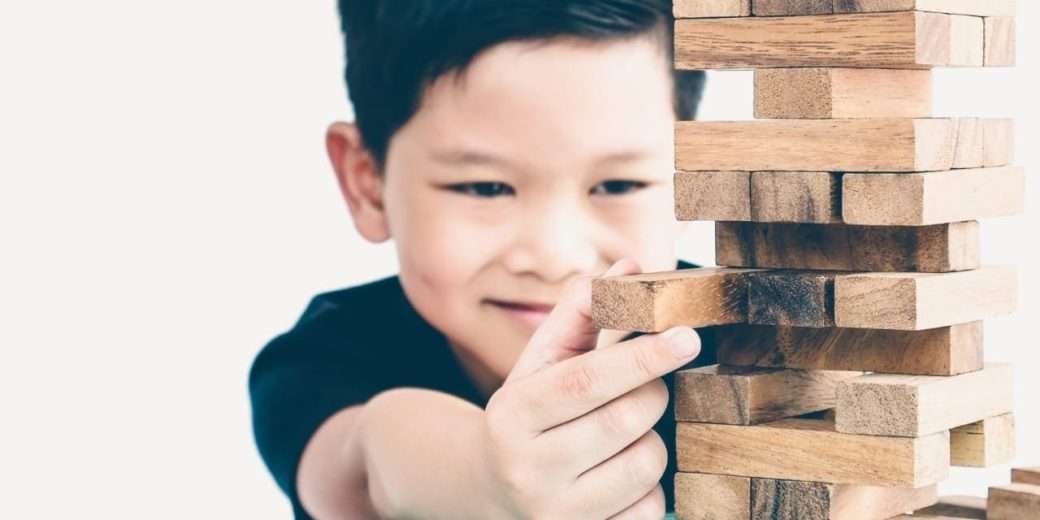 Menino brincando com peça de montar. Texto em destaque: Como a fonoaudiologia ajuda na TDAH infantil